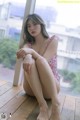 A woman in a bathing suit sitting on a wooden floor.