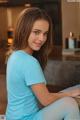 A young woman sitting on a table with a laptop.