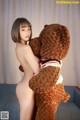 A naked woman holding a teddy bear on a couch.