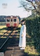 A woman in a white dress standing on a train track.