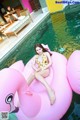 A woman in a yellow bathing suit sitting on an inflatable flamingo.